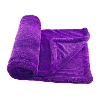 Purple plush terry towel, rolled up and partially unfolded on a white background.