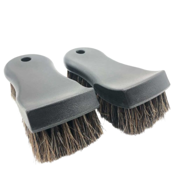 Pair of small cleaning brush heads with black plastic bases and brown stiff bristles, placed side by side.