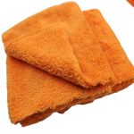 Two bright orange folded towels stacked on top of each other, showing soft terry fabric. - bravaro